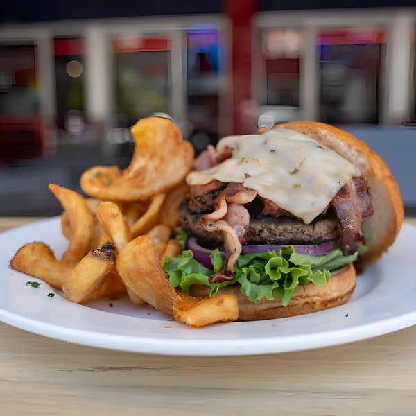 A Jams@209 bacon cheeseburger with lettuce, onion, and curly fries on a white plate.