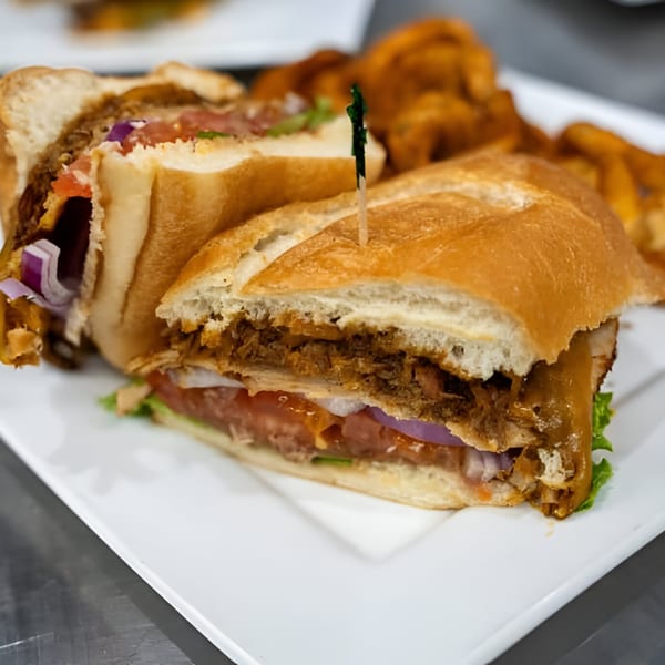 Pulled pork sandwich with lettuce, tomato, and red onion, served with curly fries.