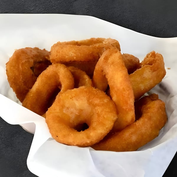 Golden-brown onion rings in a white paper-lined basket, a classic Jams@209 Sports Bar & Grill appetizer.