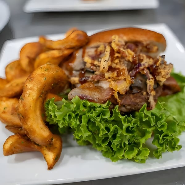 A Jams@209 Sports Bar & Grill burger with crispy onions, bacon, and curly fries.