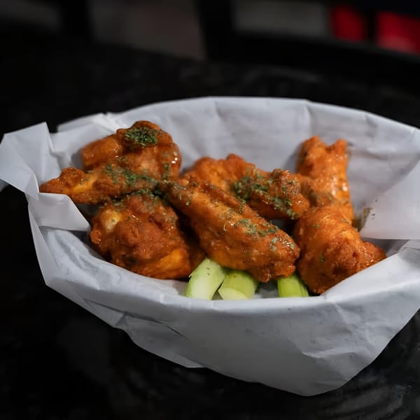 A basket of Jams@209 Sports Bar & Grill's buffalo wings with celery sticks, garnished with parsley.
