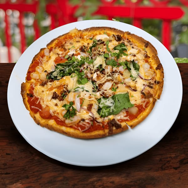 A Jams@209 Sports Bar & Grill pizza with shrimp, bacon, and greens on a white plate.