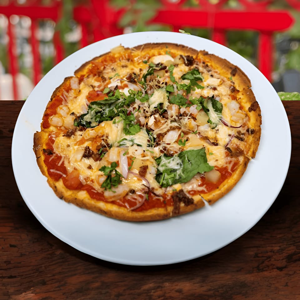 A Jams@209 Sports Bar & Grill pizza with shrimp, bacon, and greens on a white plate.