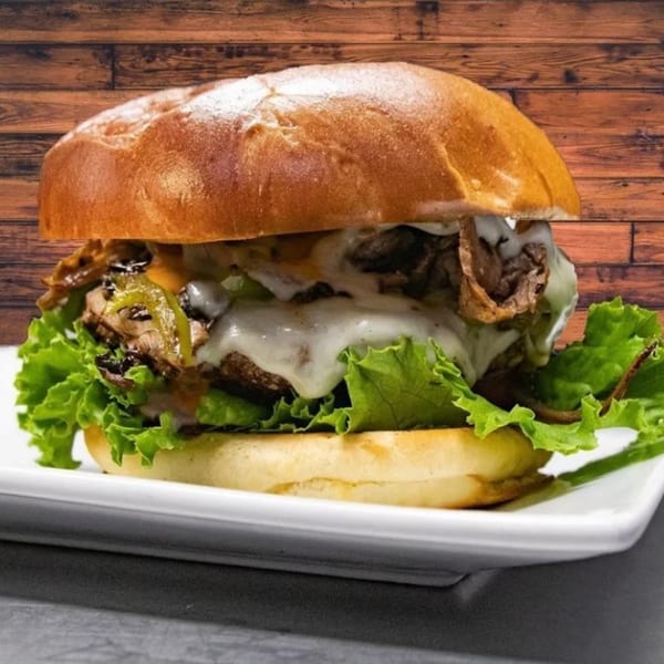 A Jams@209 Sports Bar & Grill cheesesteak sandwich with melted cheese, peppers, and lettuce.