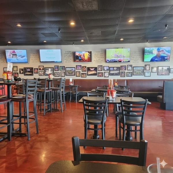 Interior of a sports bar with high-top tables, booths, and multiple TVs showing sports.