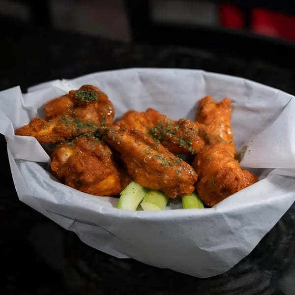 A basket of Jams@209 Sports Bar & Grill's buffalo wings with celery sticks and parsley garnish.