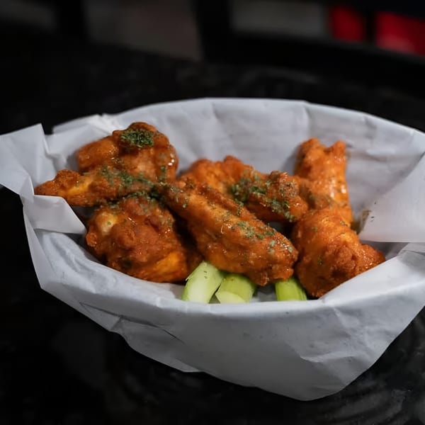 A basket of Jams@209 Sports Bar & Grill's buffalo wings with celery sticks and parsley garnish.