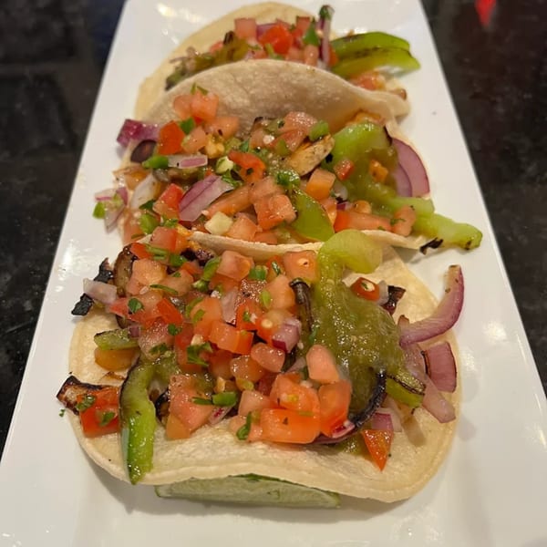 Three Jams@209 Sports Bar & Grill tacos filled with grilled vegetables, salsa, and lime wedges.