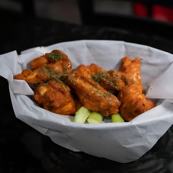 A basket of Jams@209 Sports Bar & Grill's buffalo wings with celery sticks.