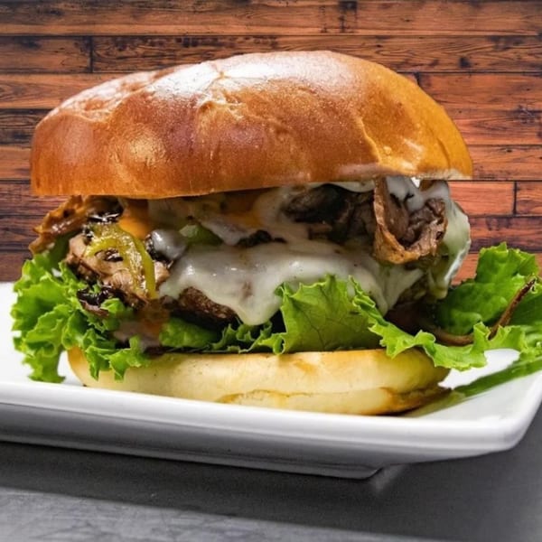 A Jams@209 Sports Bar & Grill cheesesteak sandwich with melted cheese, peppers, and lettuce.